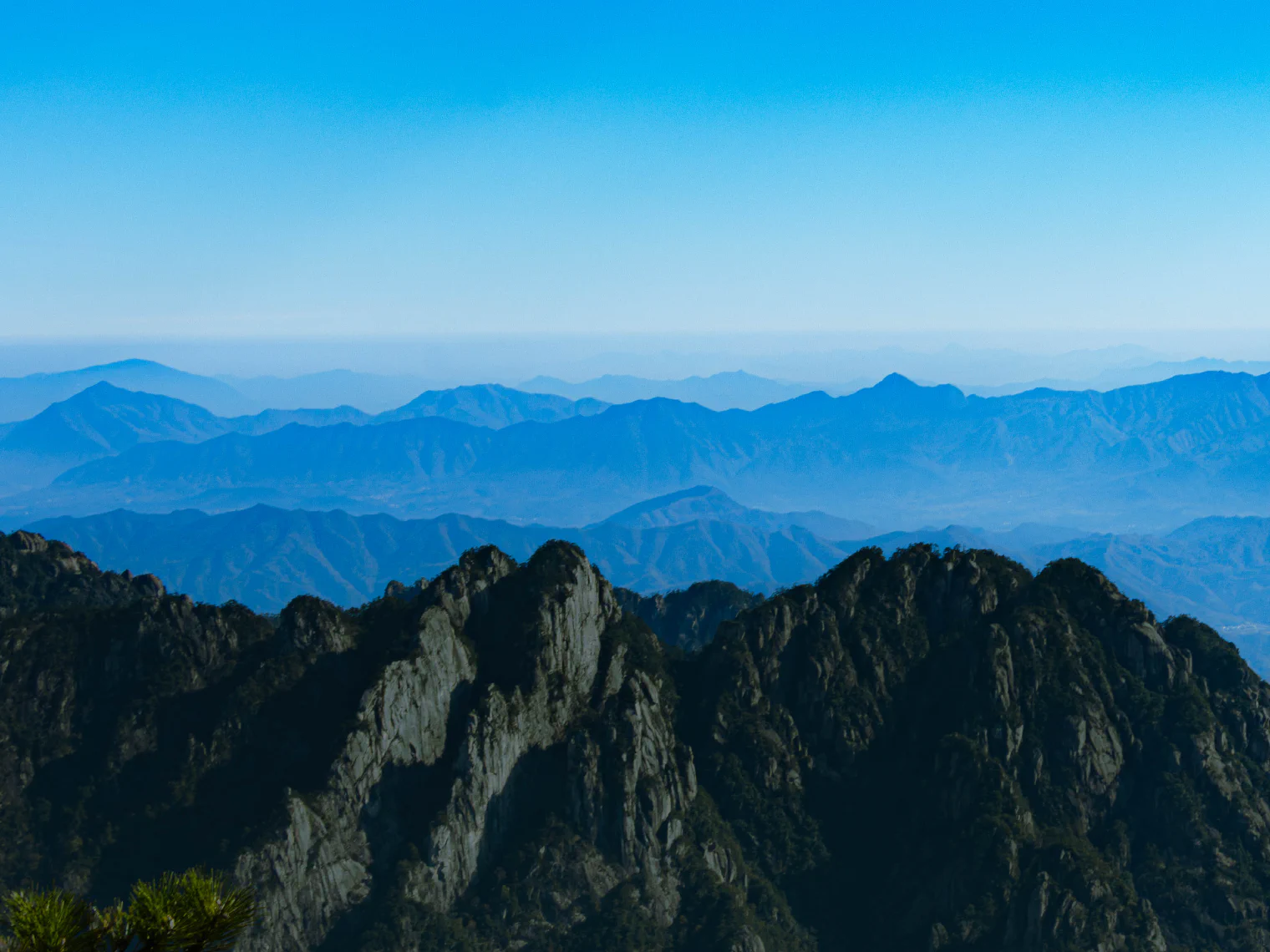 近处峭壁后，蓝色远山层层延伸。